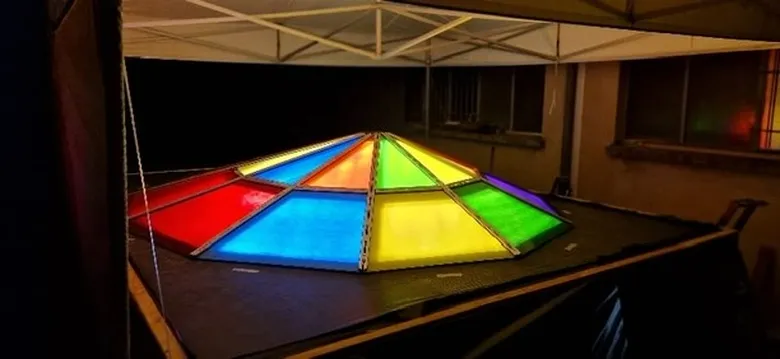 Pyramide OMNI éclairée de nuit, test lumineux des panneaux de verre, couleurs vives sur fond noir