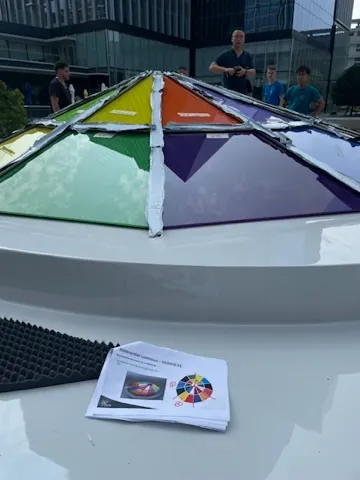 Gros plan de la Pyramide OMNI sur la coque avec une personne pour l'échelle, panneaux de verre colorés