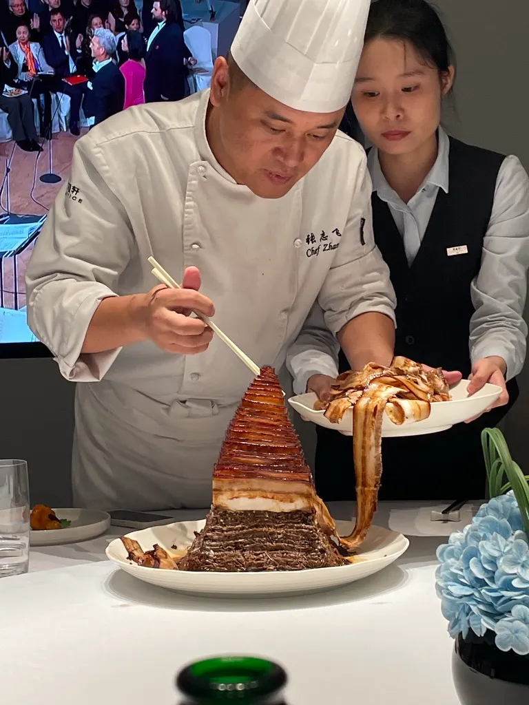 Chef Zhao au gala Winland présentant une sculpture culinaire inspirée de la Pyramide OMNI Hangzhou